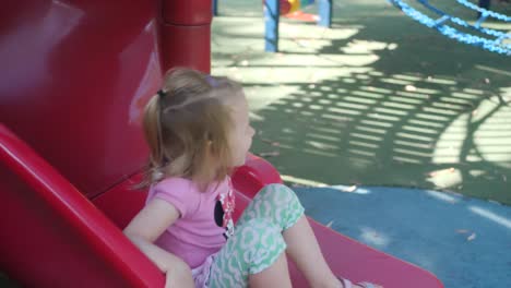 slow motion of a 4 year old girl on a slide smiling happily