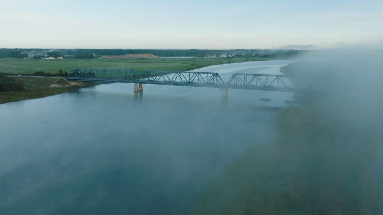 ⁇ 은 여름 아침에 젤루페 강을 가로지르는 철강 다리의 공중 뷰, 강 위로 떠오르는 안개, 달리는 자동차, 앞으로 나아가는 넓은 드론  ⁇