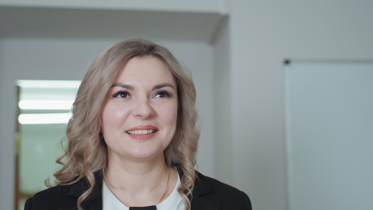 Smiling professional lady enters office with warm cheerful expression, confident demeanor, and natural poise, framed by soft lighting and minimal background