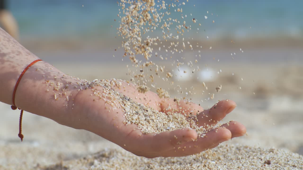 Sand falling from hand in slow motion on a beach. Vacation and travel concept. Shot on super slow motion camera 1000 fps.
