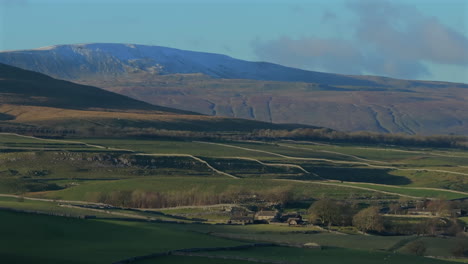 establishing drone shot of yorkshire dales farmland with whernside behind