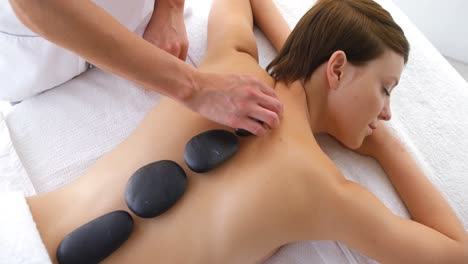 Woman-therapist-putting-hot-stones