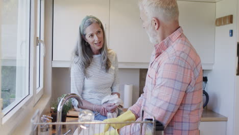 Pareja-Caucásica-De-Mediana-Edad-Lavando-Platos-En-La-Cocina-De-Casa,-Cámara-Lenta