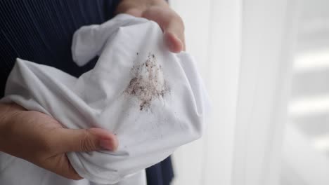 a person holding a white shirt with a brown stain on it