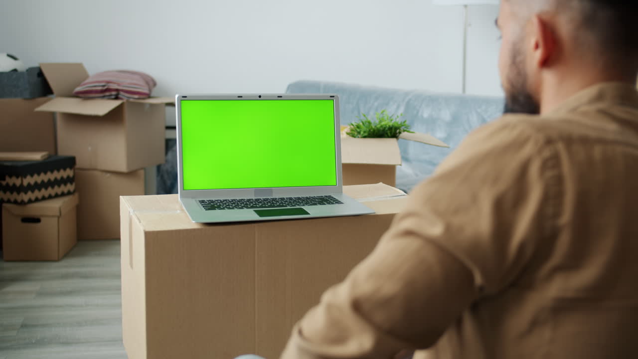 Man using a laptop with a green screen in a moving house
