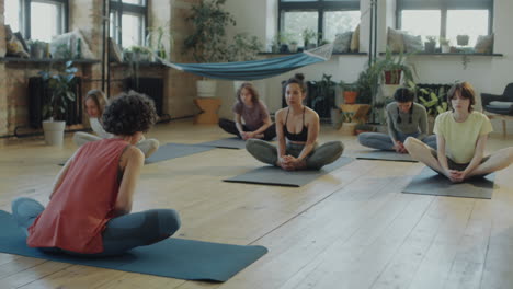 girls doing butterfly stretch on group yoga class
