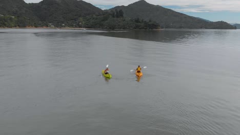 slowmo - two people kayaking with yachts in background in marlborough sounds, new zealand - aerial