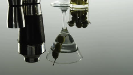 grey paper burning over bartender equipment and olives in cocktail glass on grey background