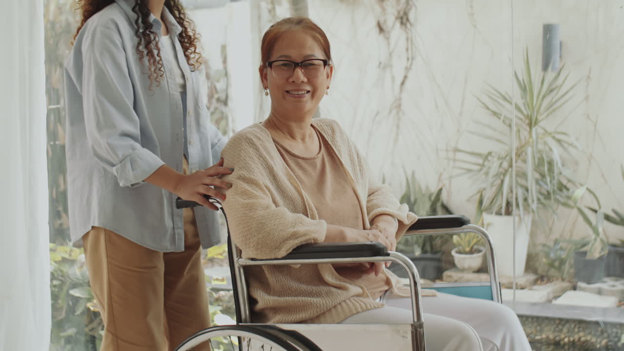 Elderly Woman Assisted in Wheelchair by Caregiver