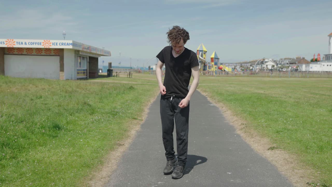 검은 옷을 입은 젊은 성인 남성이 따뜻해지고 앞으로 뛰어다니고 있습니다.