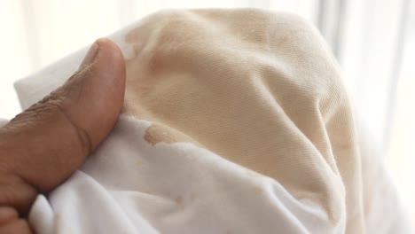 primer plano de una mancha marrón en una camisa blanca