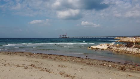 Aerial-view-flying-low-over-the-beach-towards-the-Hadera-port-in-sunny-Israel