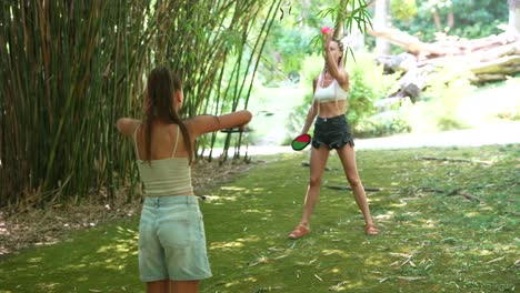 two women playing a game outdoors in a bamboo park