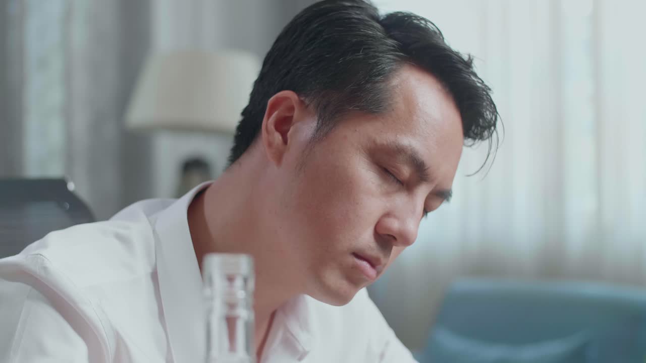 집에서 노트북으로 타이핑하는 동안 보드카를 마시는 아시아 남자의 클로즈업