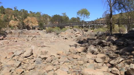 a dry riverbed, blue sky, bridge and trees, panning shot right to left