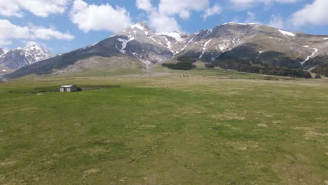 wide angle scene of an old sheppards shelter in a grassland valley surrounded by the gran sasso mountain range in the rural countryside of abruzzo in italy