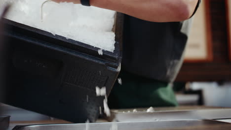 Throwing-crushed-ice-from-box-into-ice-container-of-festival-stand