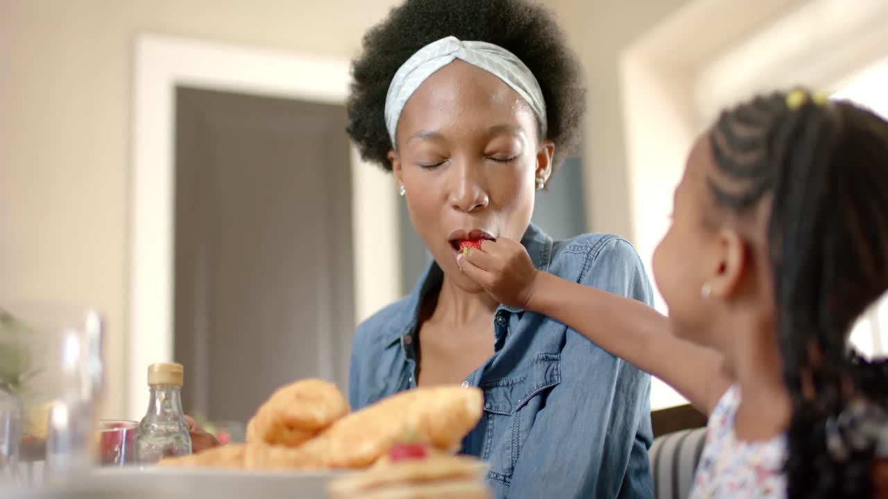 Heureuse mère et fille afro-américaines prenant le petit-déjeuner, au ralenti