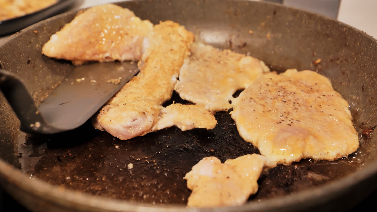Close-up of seasoned chicken schnitzels frying to golden brown, home kitchen pan