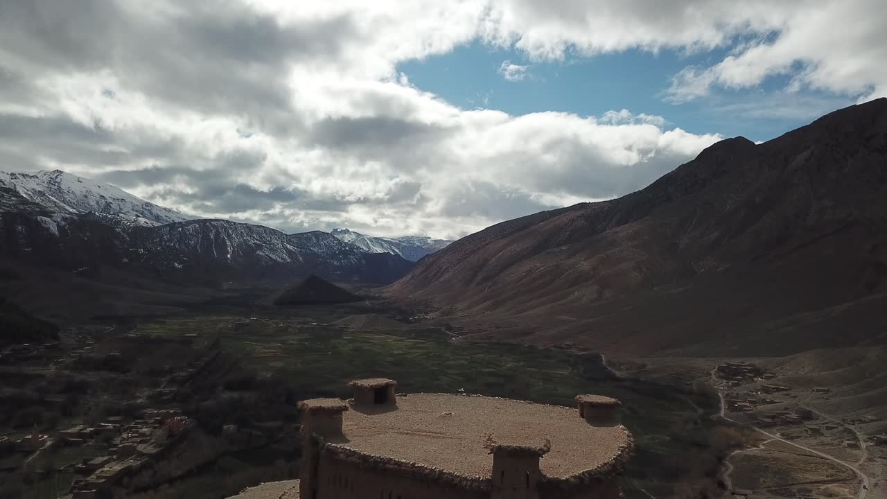 "A majestic fortress perches atop a rocky hill amid Morocco's Atlas peaks, its traditional mud-brick architecture and watchtowers commanding sweeping views of the surrounding valleys