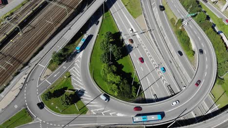 aerial view overlooking traffic on a highway intersection and railway, sunny day, in sweden - high angle, drone shot