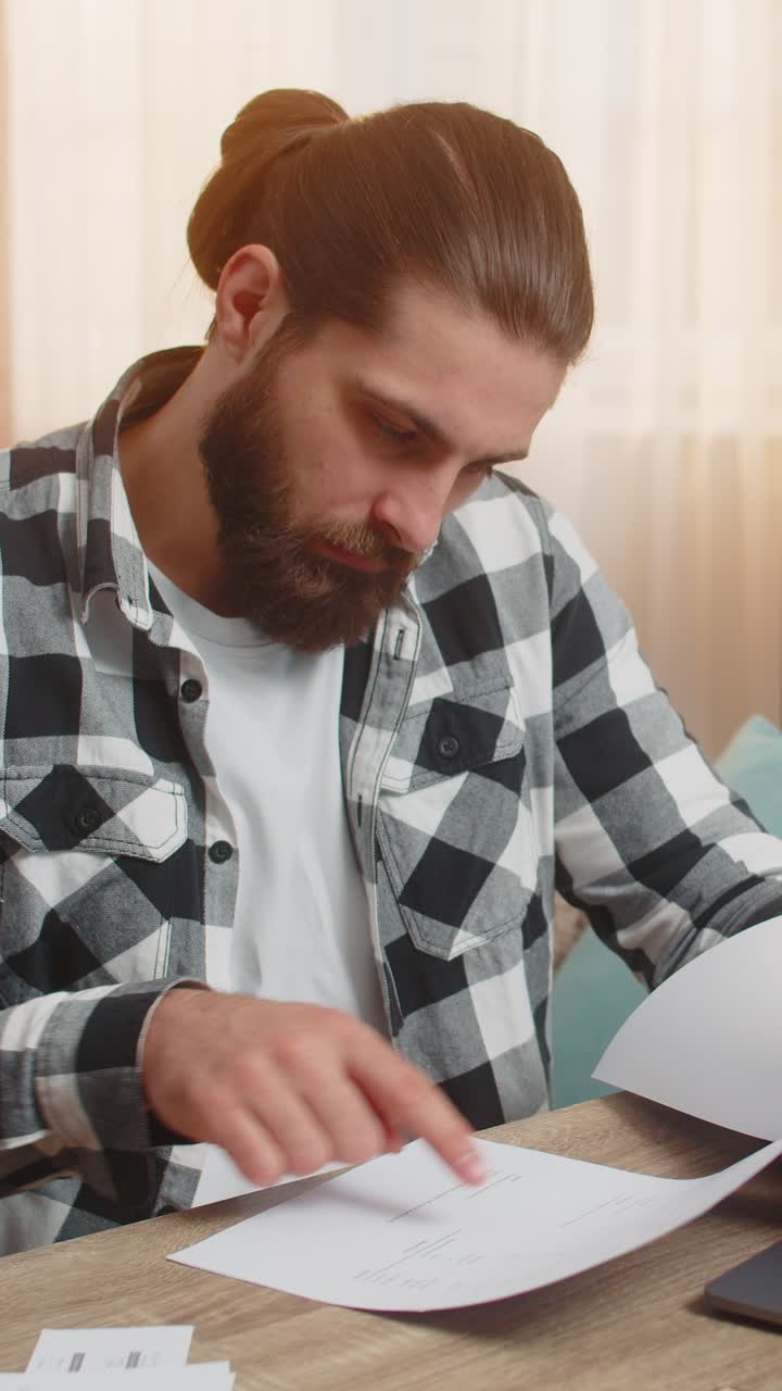 un hombre serio analiza el contrato con un banco en casa. la mesa se agarra a la cabeza con cláusulas de condiciones complejas.