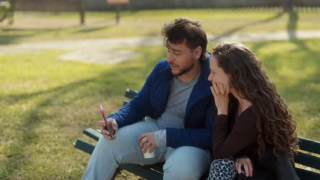 couple taking a selfie and relaxing on a park bench