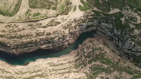 aerial overhead shot of the canyon wied il-għasri with a beautiful clear turquoise water