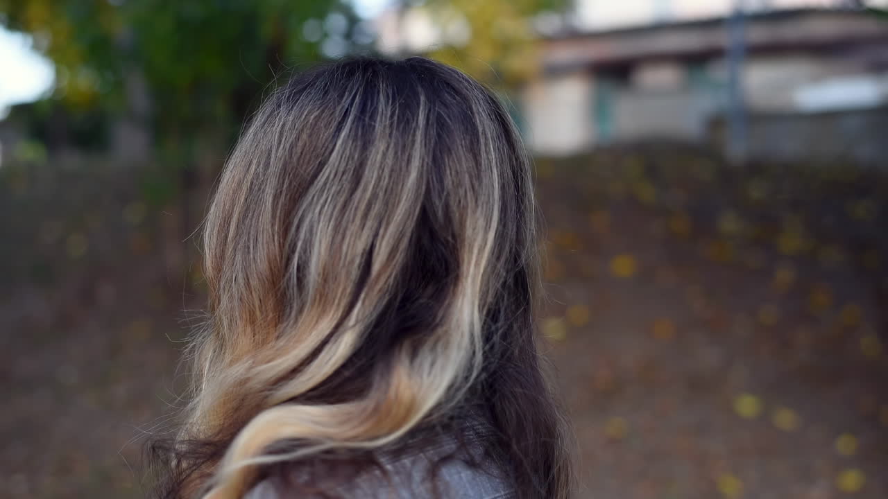 Close up of a blonde woman turning and smiling at the camera in the park