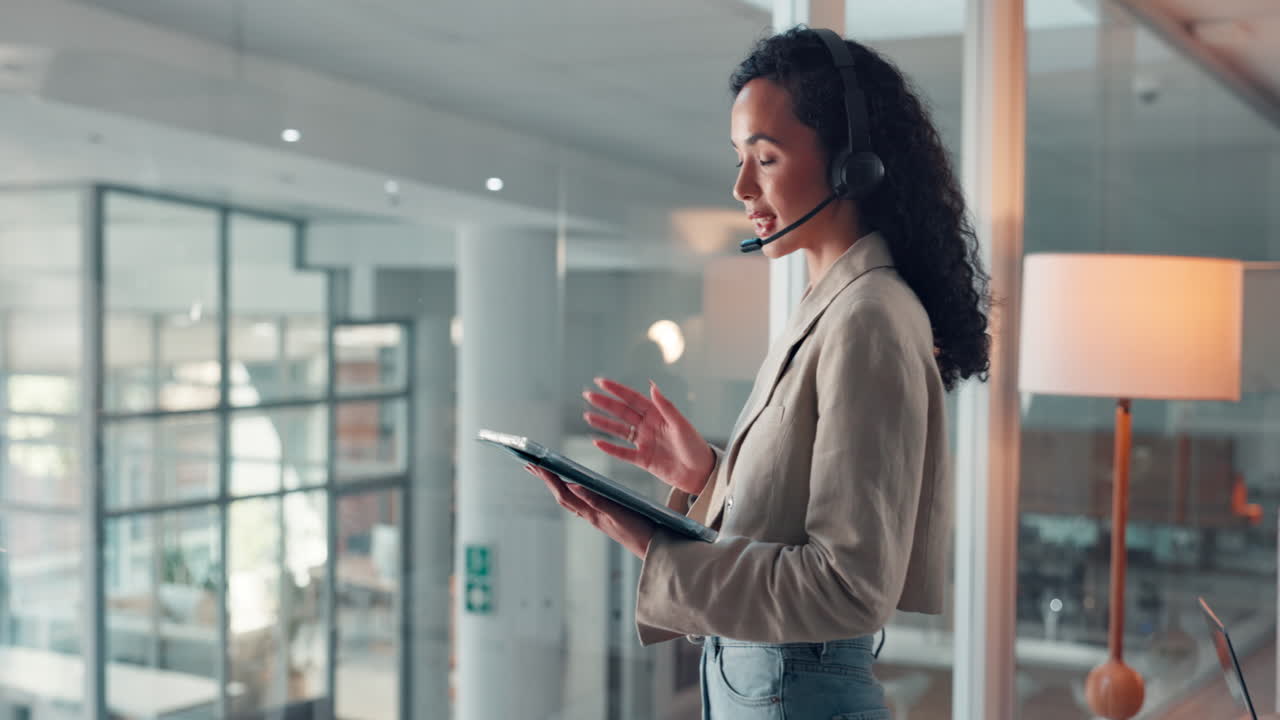 Forretningskvinne med headset som bruker nettbrett på kontoret