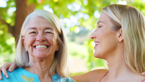 portrait of multi-generation family with senior mother and adult daughter laughing in garden