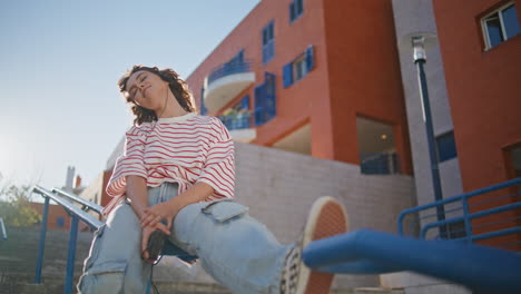 woman listening music staircase wearing earphones enjoying summer sunlight.