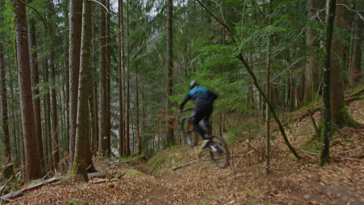 un ciclista de montaña da un gran salto a gran velocidad en un bosque