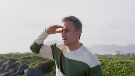 caucasian man enjoying free time by sea on sunny day looking away