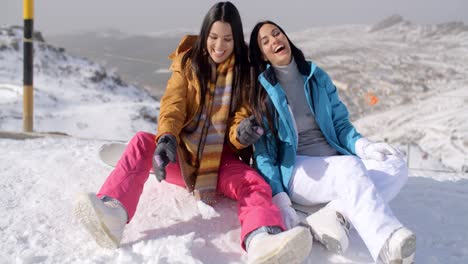 Two-young-female-snowboarders-enjoying-a-chat