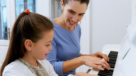 mother assisting daughter in playing piano 4k