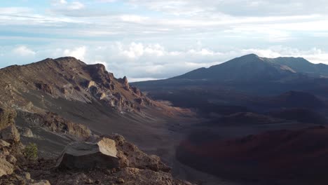 Stunning-still-view-of-a-dawn-with-the-sun,-crater-and-puffy-cloud-cover-at-the-top-of-volcano-summit-crater-at-Haleakala-National-Park-which-is-a-massive-shield-volcano,Maui,Hawaii,USA