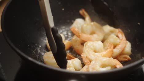 unrecognizable cook frying prawns in pan with hot oil