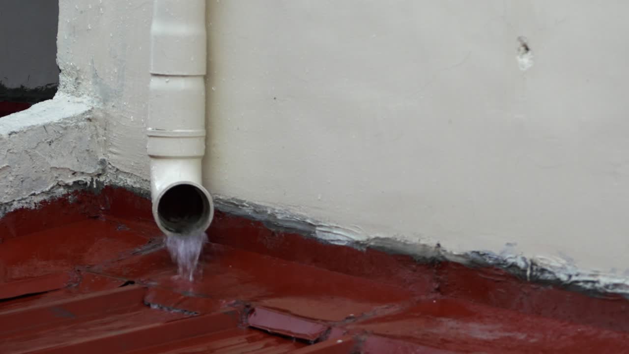 el agua de lluvia del canalón superior sale de un canalón de drenaje residencial durante una llovizna