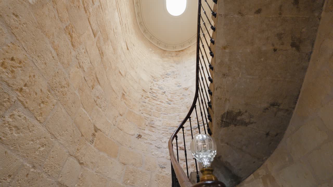 Slow tilting shot revealing a spiral stone staircase within a villa in Baillargues