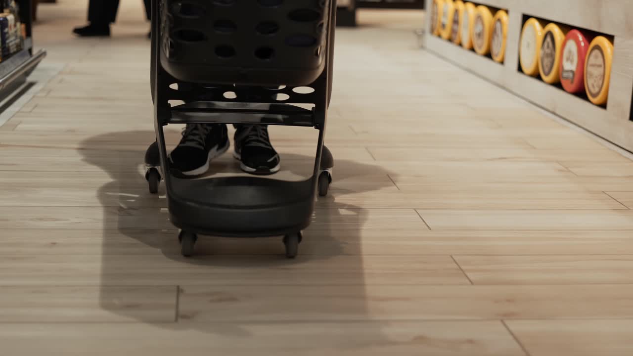 スーパーマーケットの食料品通路に沿ってトロリーを押している男性 ⁇ フロントクロップビュー