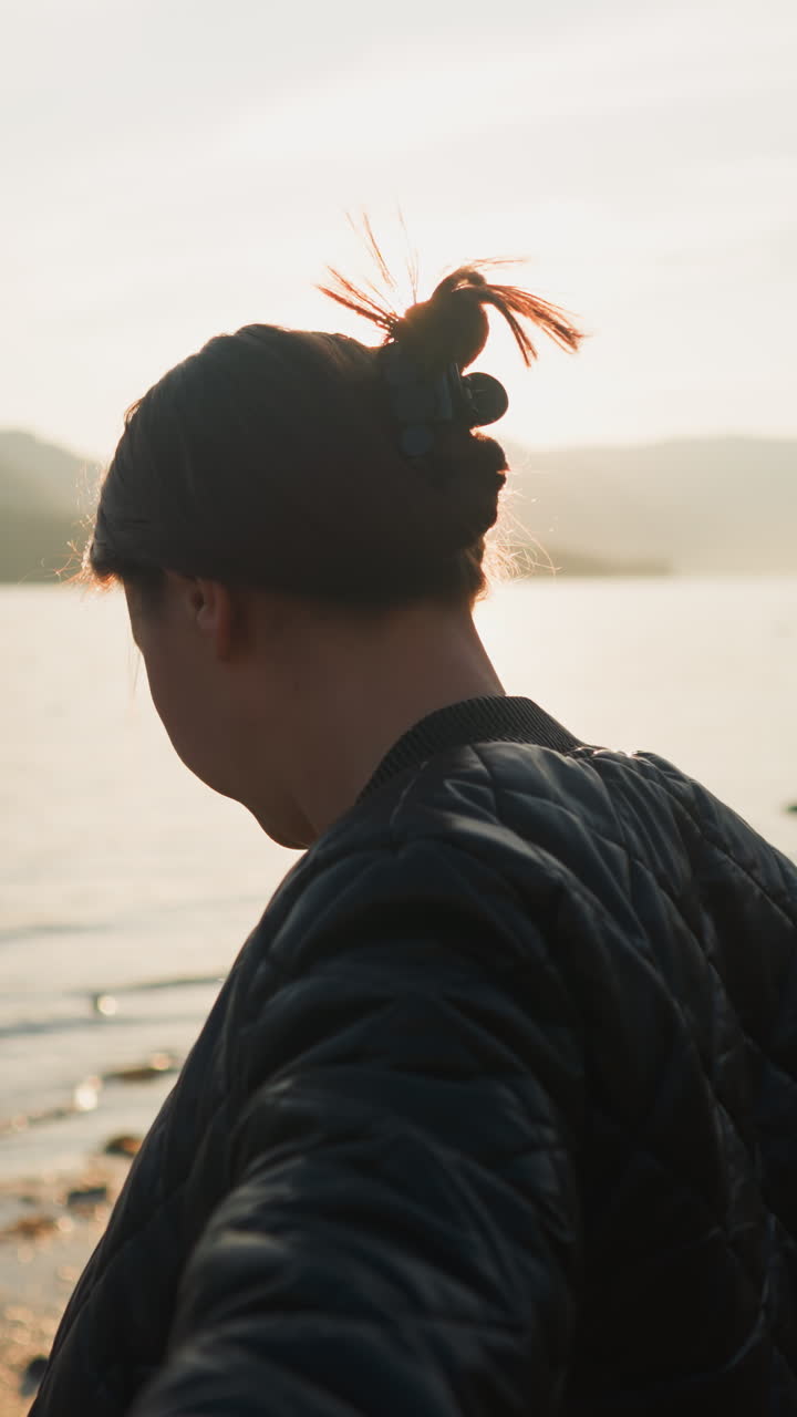 Wife holds husband hand on riverbank at sunset. Romance blossoms between young couple during sharing holidays among rural landscape. Optimistic moments of life