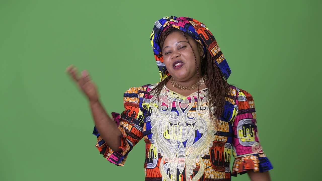 Overweight beautiful African woman wearing traditional clothing against green background