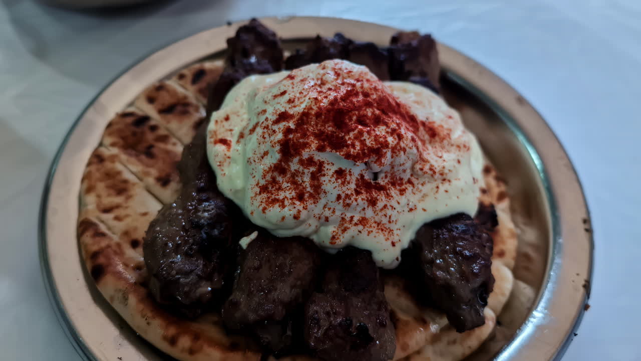 Sarımsaklı ekmek üzerinde kuzu köftesi ve cacık, tipik bir Yunan yemeğidir.