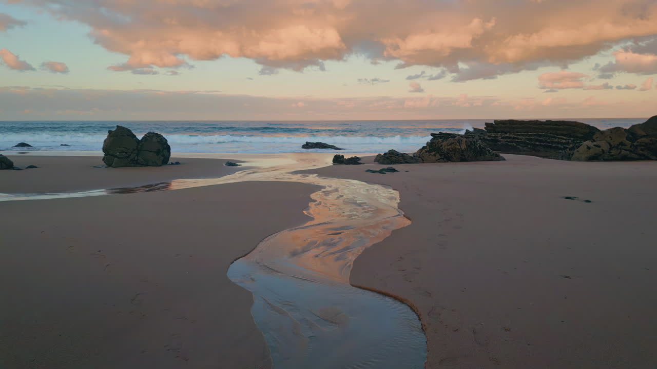 Golden sunset lighting beach in drone view. Waves gently washing over sandbanks