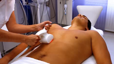 médico que realiza la depilación láser en un paciente masculino