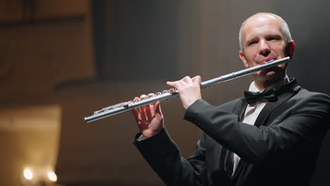 professional flutist is playing melody in old opera house portrait of talented aged musician