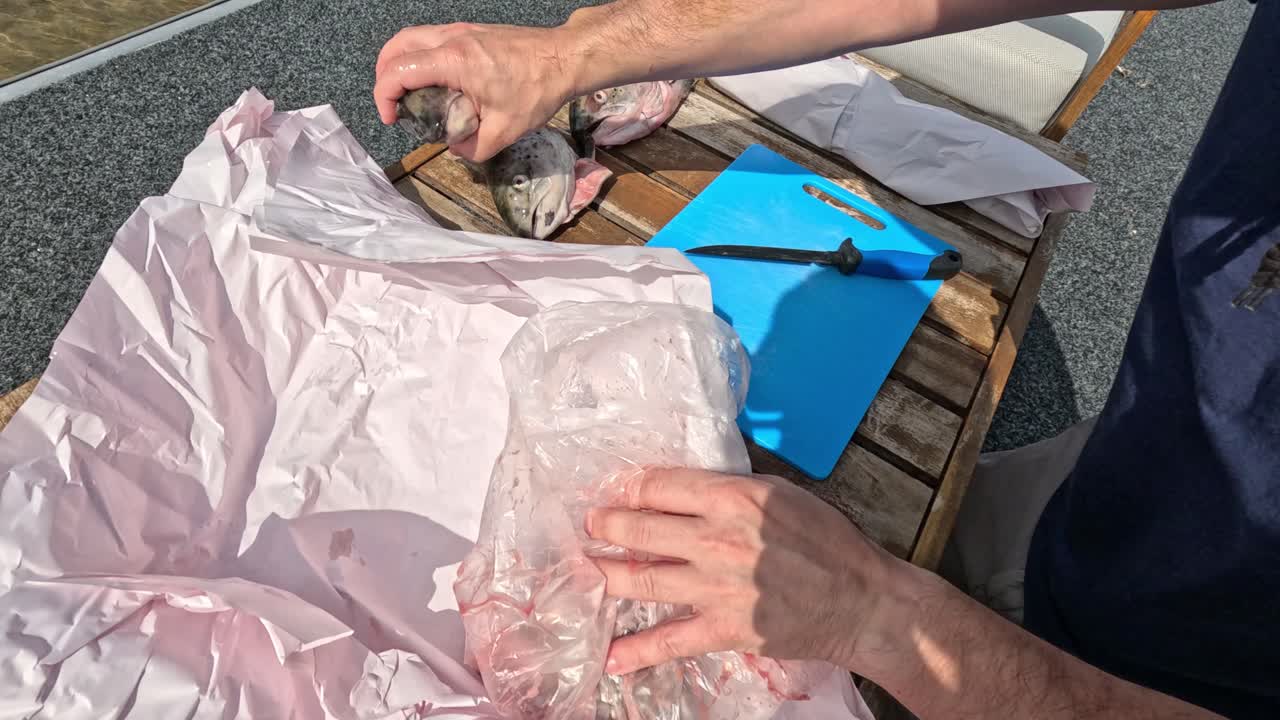 두 사람 이 야외 에서 물고기 를 풀고 준비 하고 있다