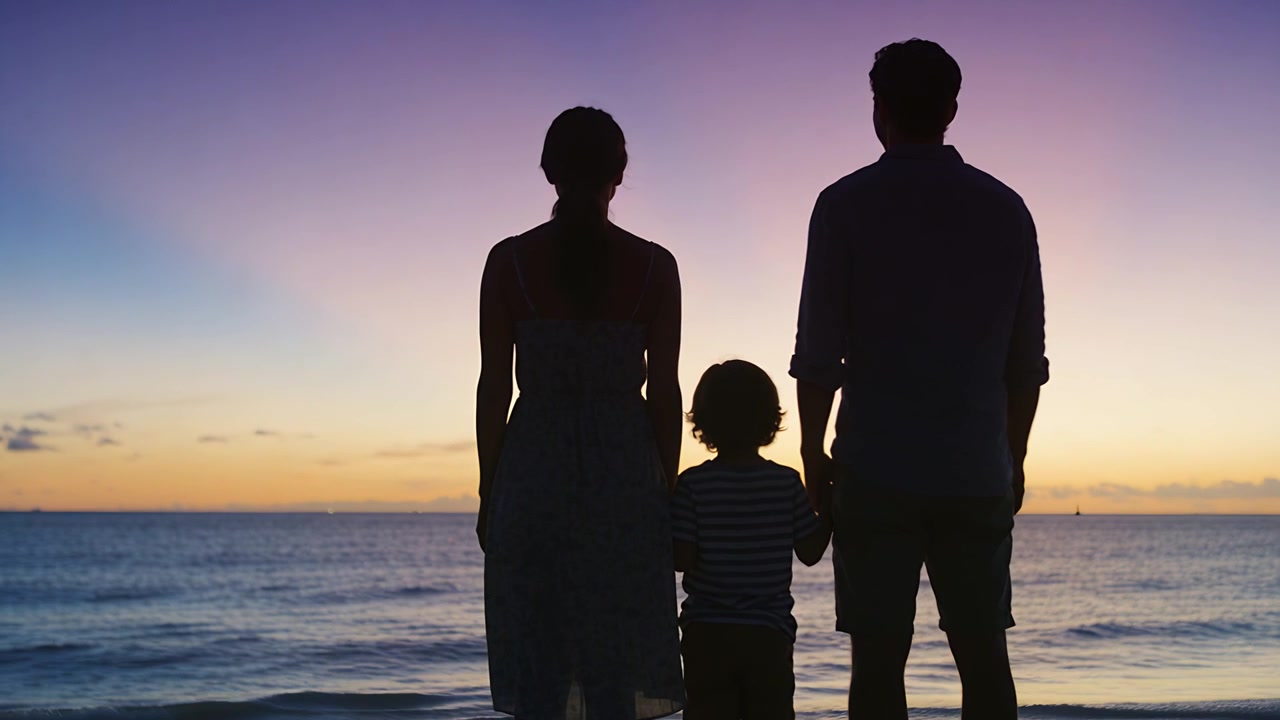 Una famiglia in piedi che si tiene per mano guarda il tramonto sulla riva del mare, con il bagliore dell'orizzonte che si intensifica.
