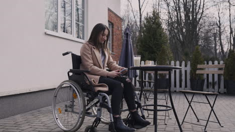 happy disabled girl in wheelchair using mobile phone in a bar terrace 1